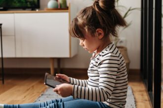 portrait little woman jeans t shirt sitting carpet holding tablet